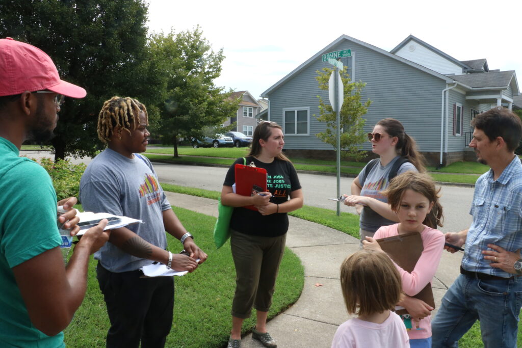 A group of canvassers chat on a street corner in West Louisville.